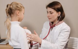 Family doctor in Boise uses stethoscope to examine young girl during a sick visit at a primary care clinic